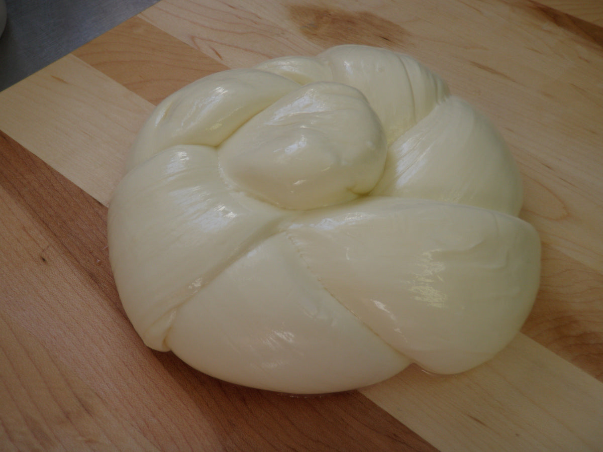 A hand-braided round of fresh mozzarella on a maple board