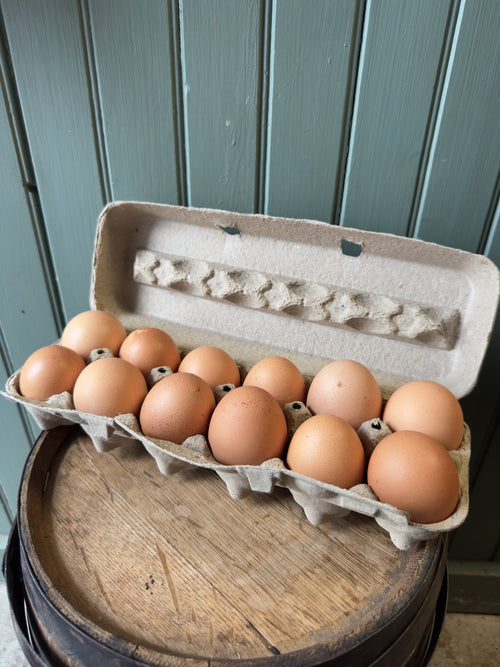 Open carton of a dozen brown Flint Hill Farm eggs on a wooden barrel