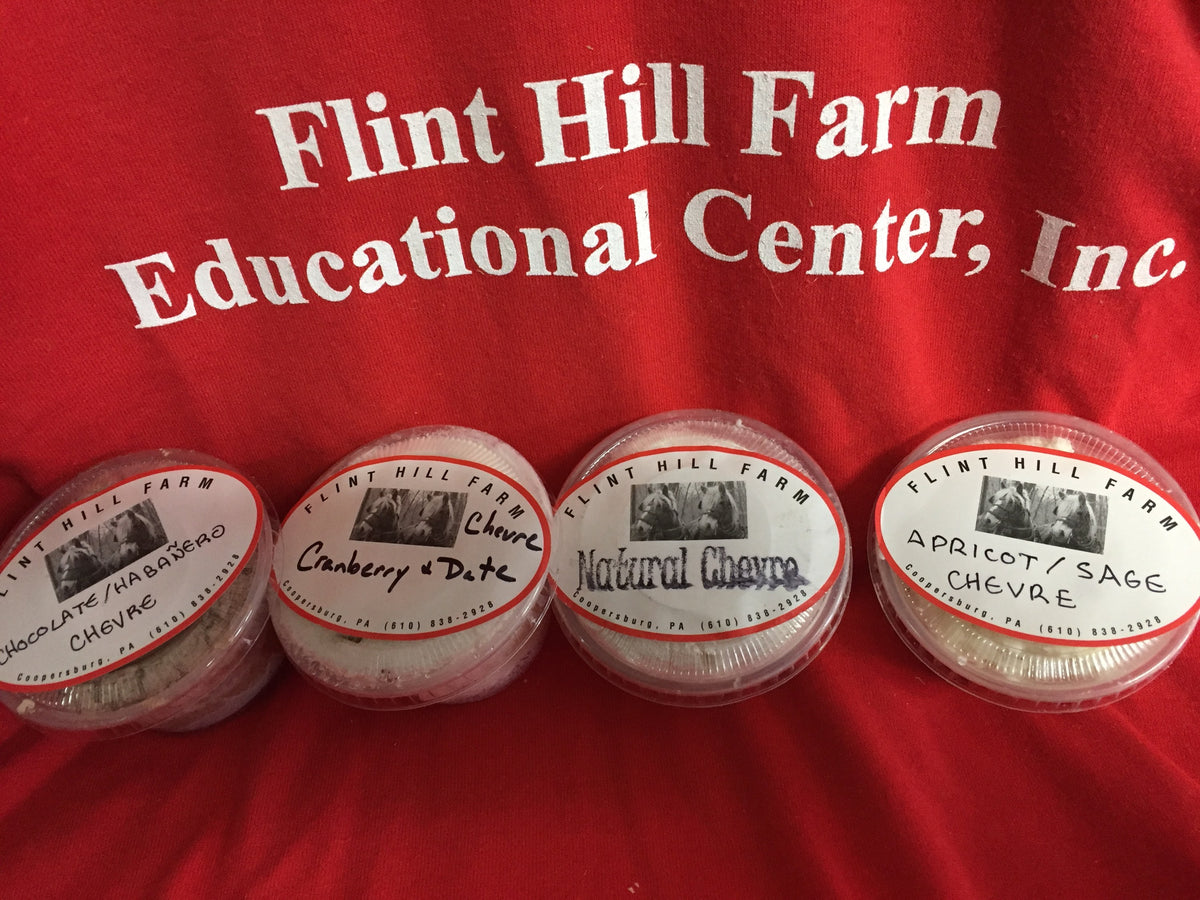 Four 4-oz tubs of Flint Hill Farm chevre on a red farm T-shirt: Chocolate/Habanero, Cranberry & Date, Natural and Apricot/Sage