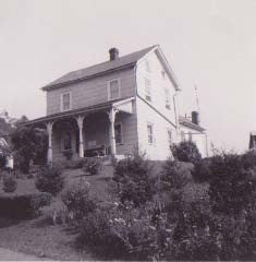 Archival photo of the Flint Hill Farm farmhouse in 1910, a two-story clapboard house with a full-width porch, donated by the Cicione family