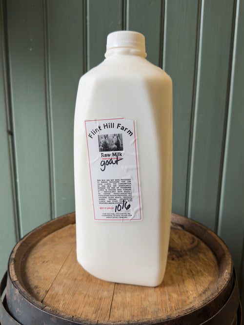 Half gallon of Flint Hill Farm raw goat milk on a wooden barrel