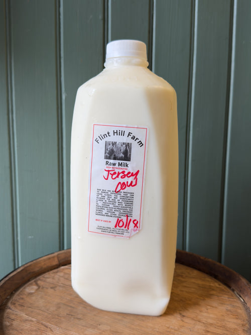Half gallon of Flint Hill Farm raw Jersey cow milk on a wooden barrel