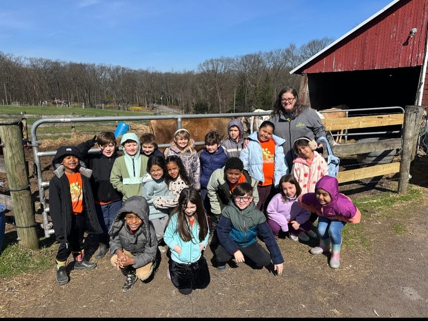 A school group posing with a counselor at the cattle pen