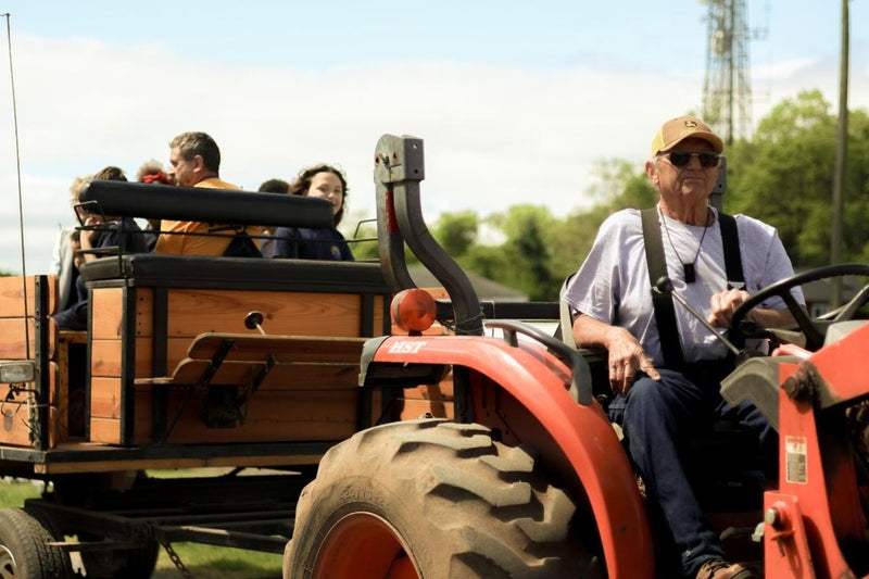 A farmhand driving a tractor pulling a hayride wagon
